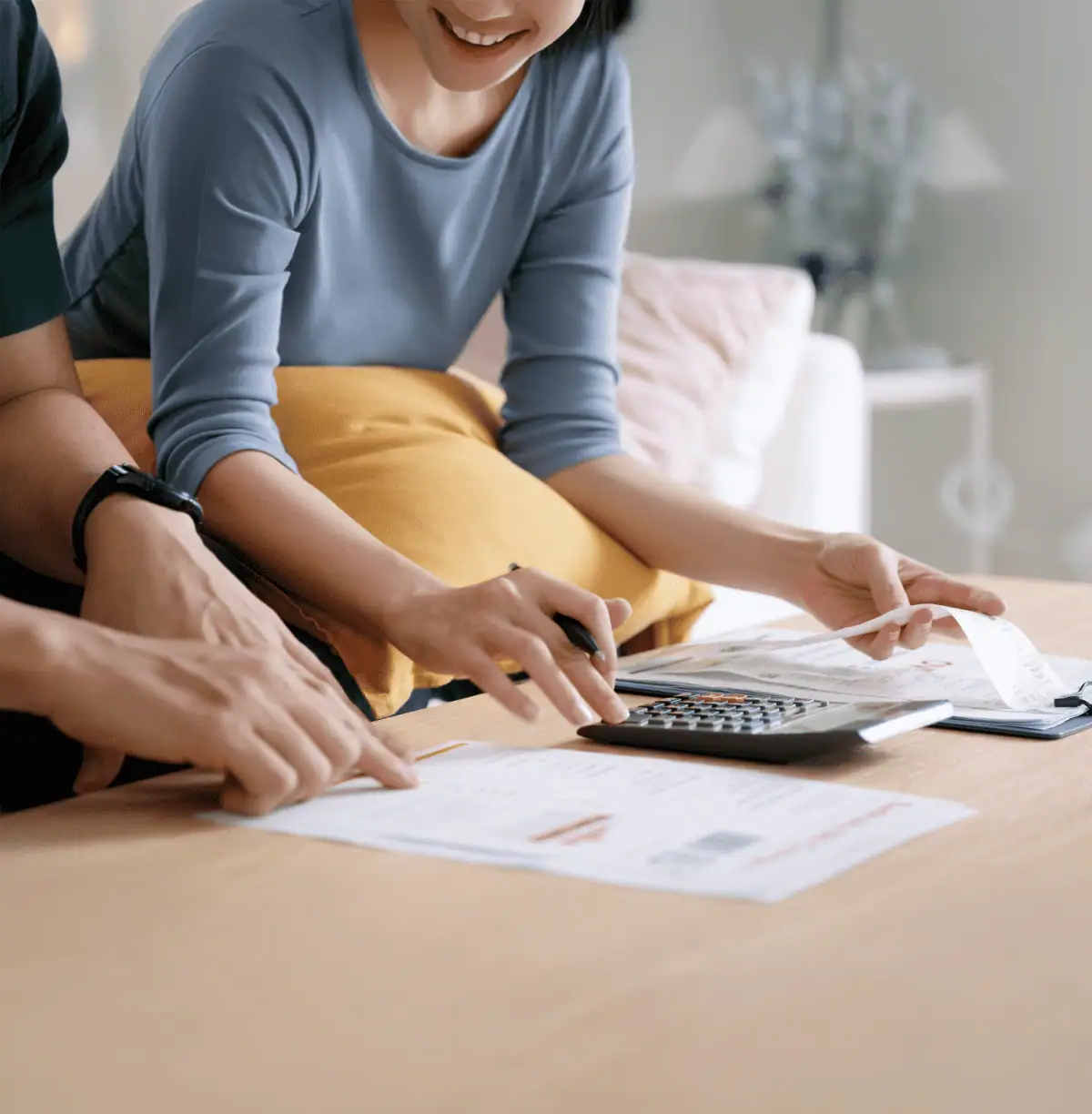 Couple sitting on a couch looking at paperwork and using a calculator
