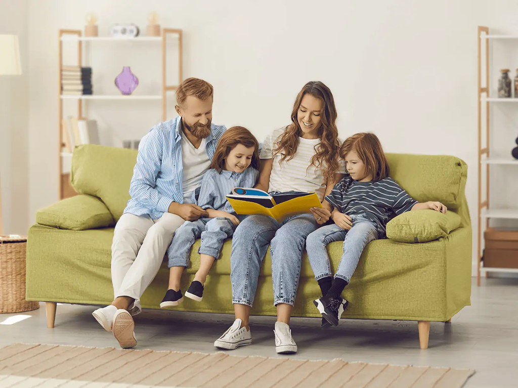 Family sitting on a couch and looking at a book