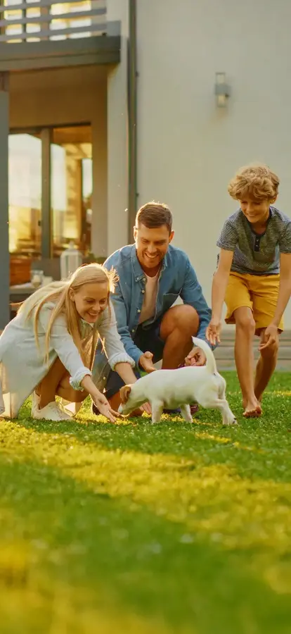 Family Playing with Dog on Lawn in front of house