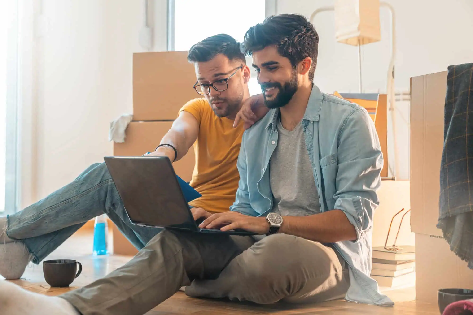 Two people sitting on the floor and looking at a laptop