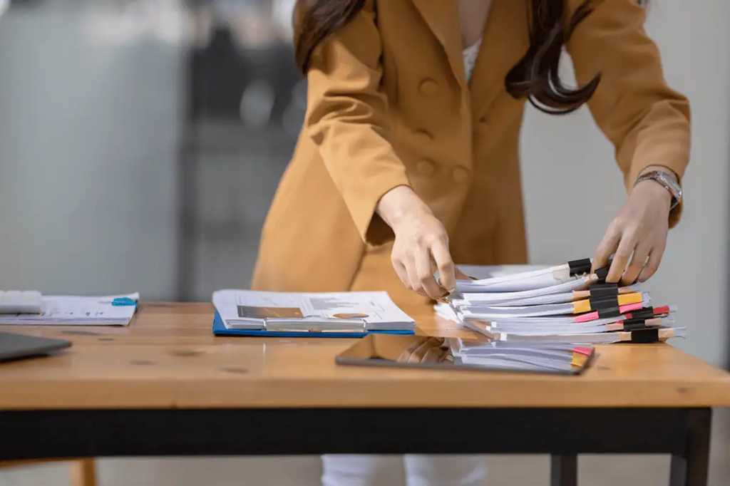 person looking through stacks of papers on desk