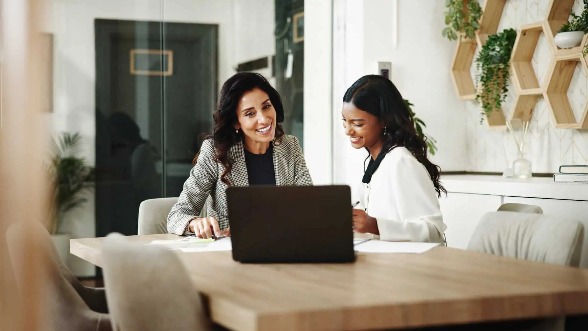 Two women at a table with a laptop and papers
