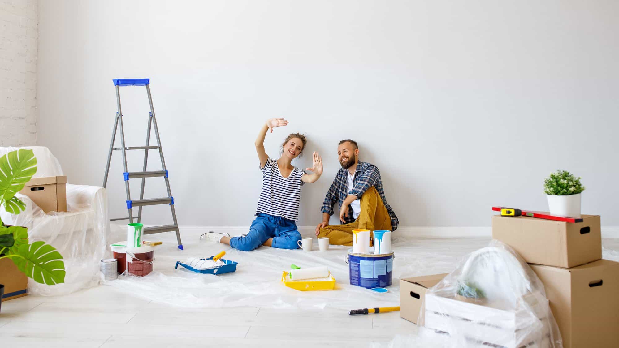 A couple sitting on the floor with painting supplies
