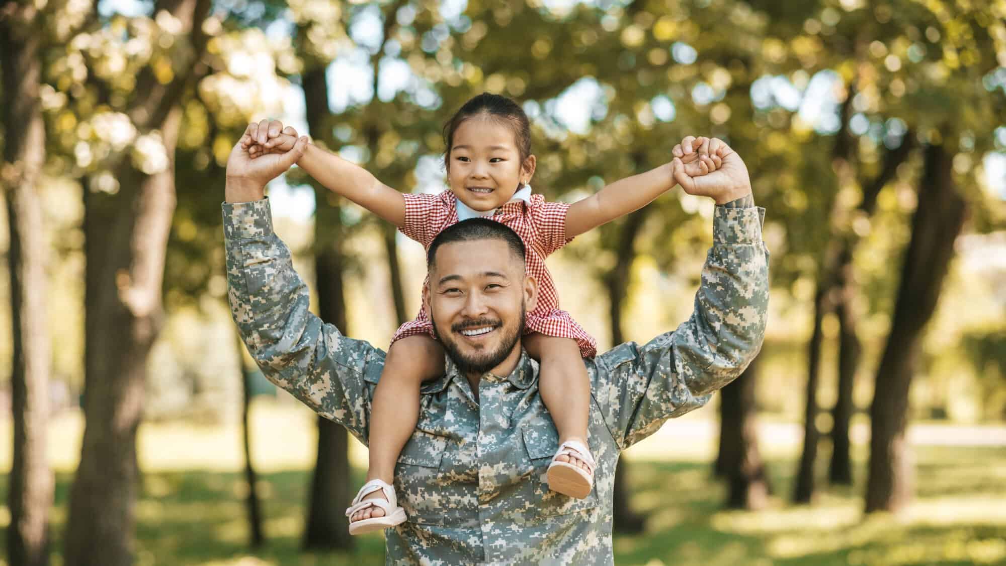 Man in military fatigues with child on shoulders