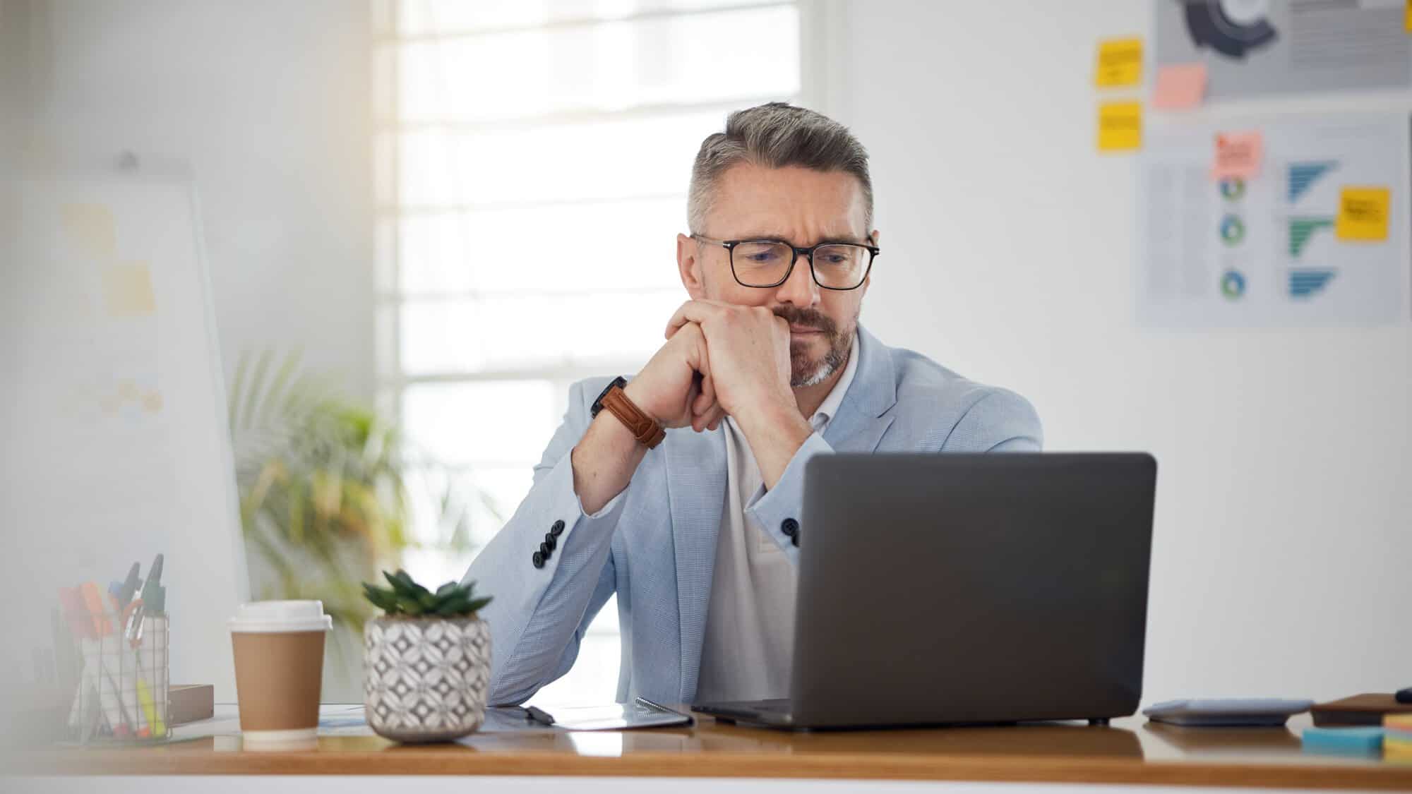 A guy with glasses looking at a laptop