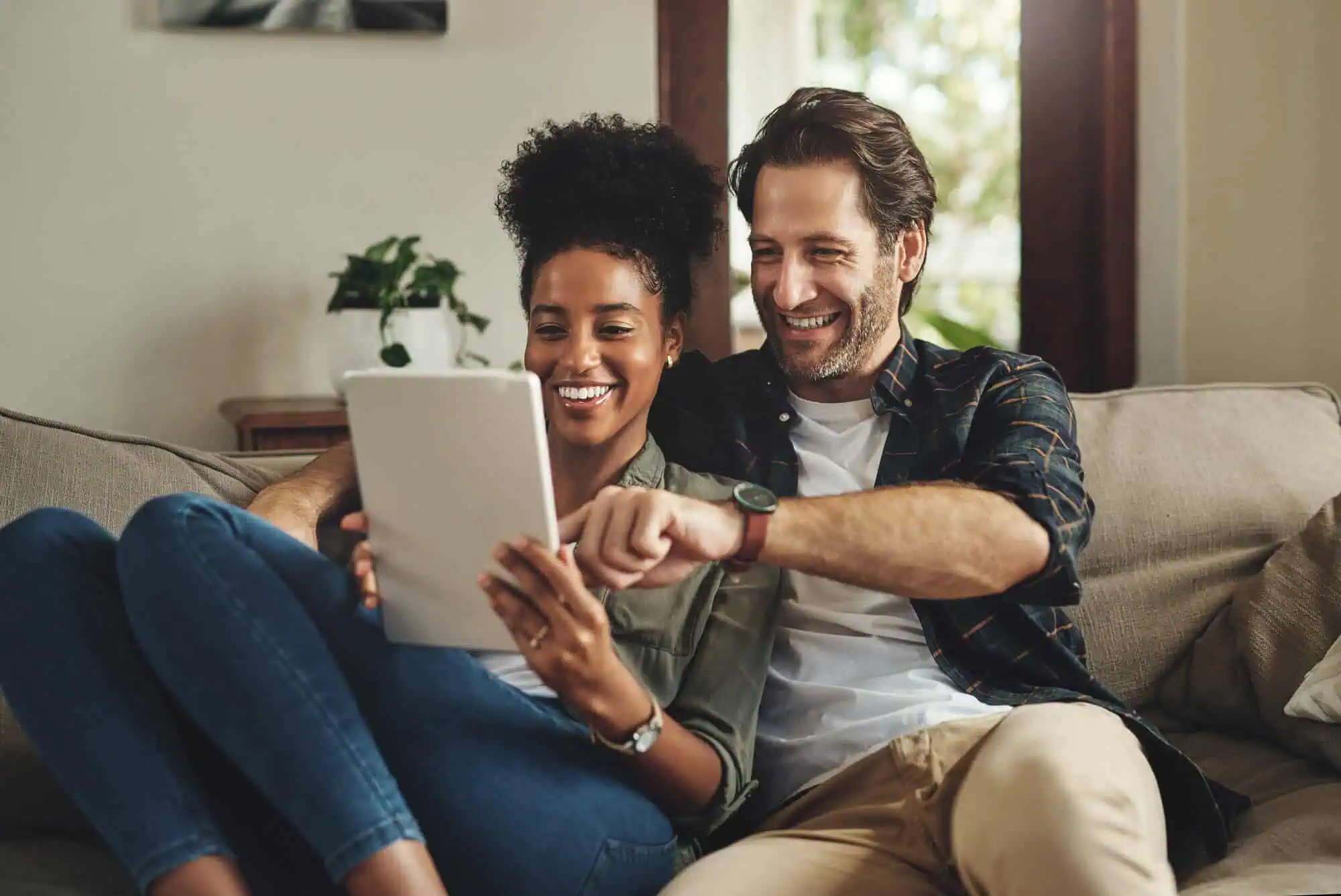 A couple on a couch looking at a tablet
