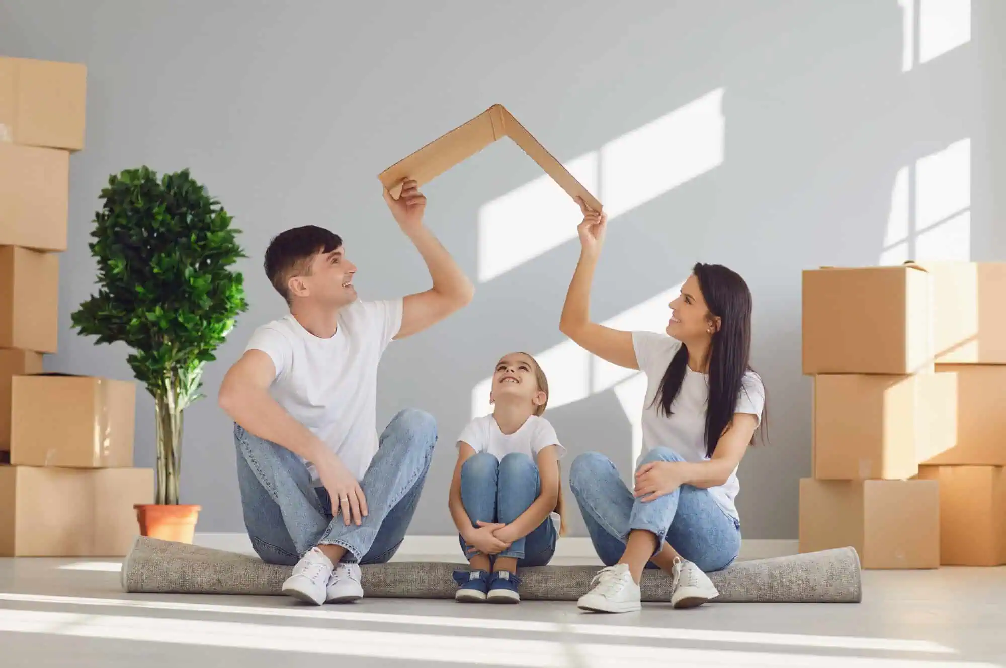 A couple holding a bent piece of cardboard over a child