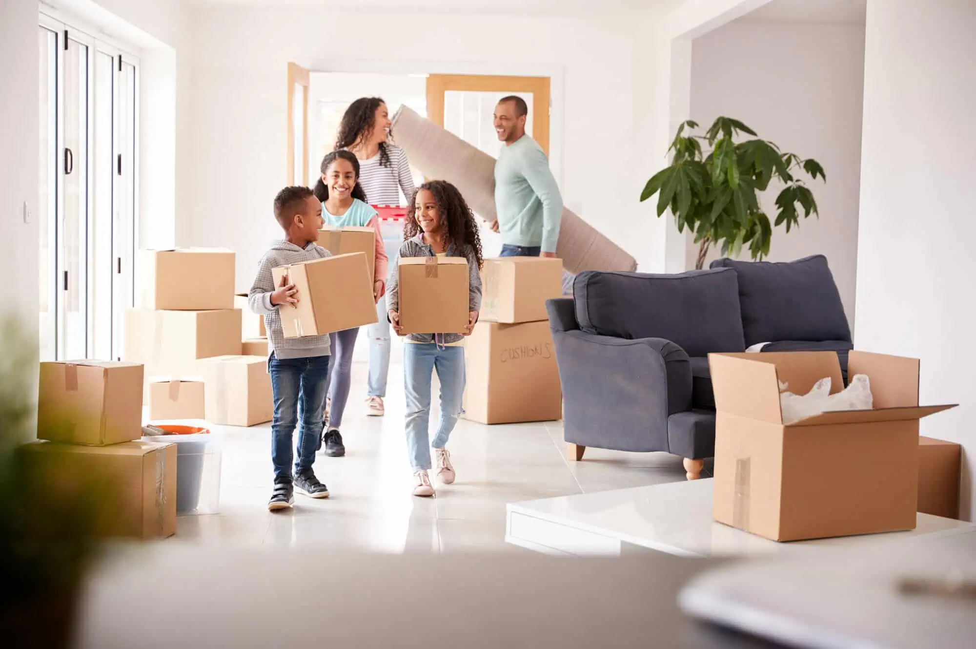 Family in a house carrying boxes and a rug