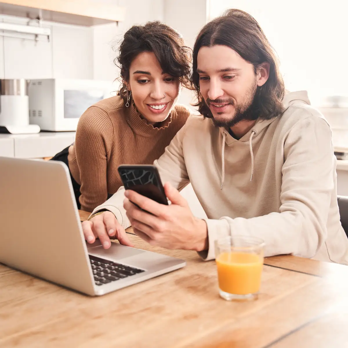 couple looking at phone at laptop