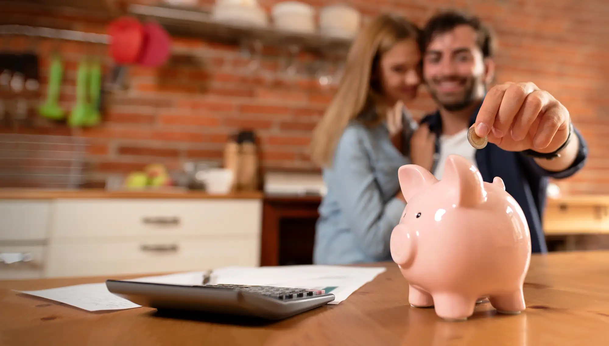 couple dropping coin in piggy bank