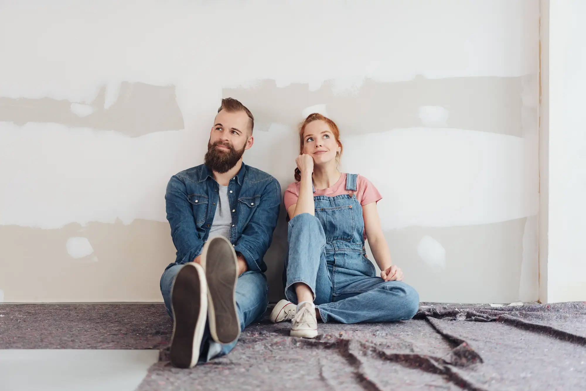 couple sitting against bare wall