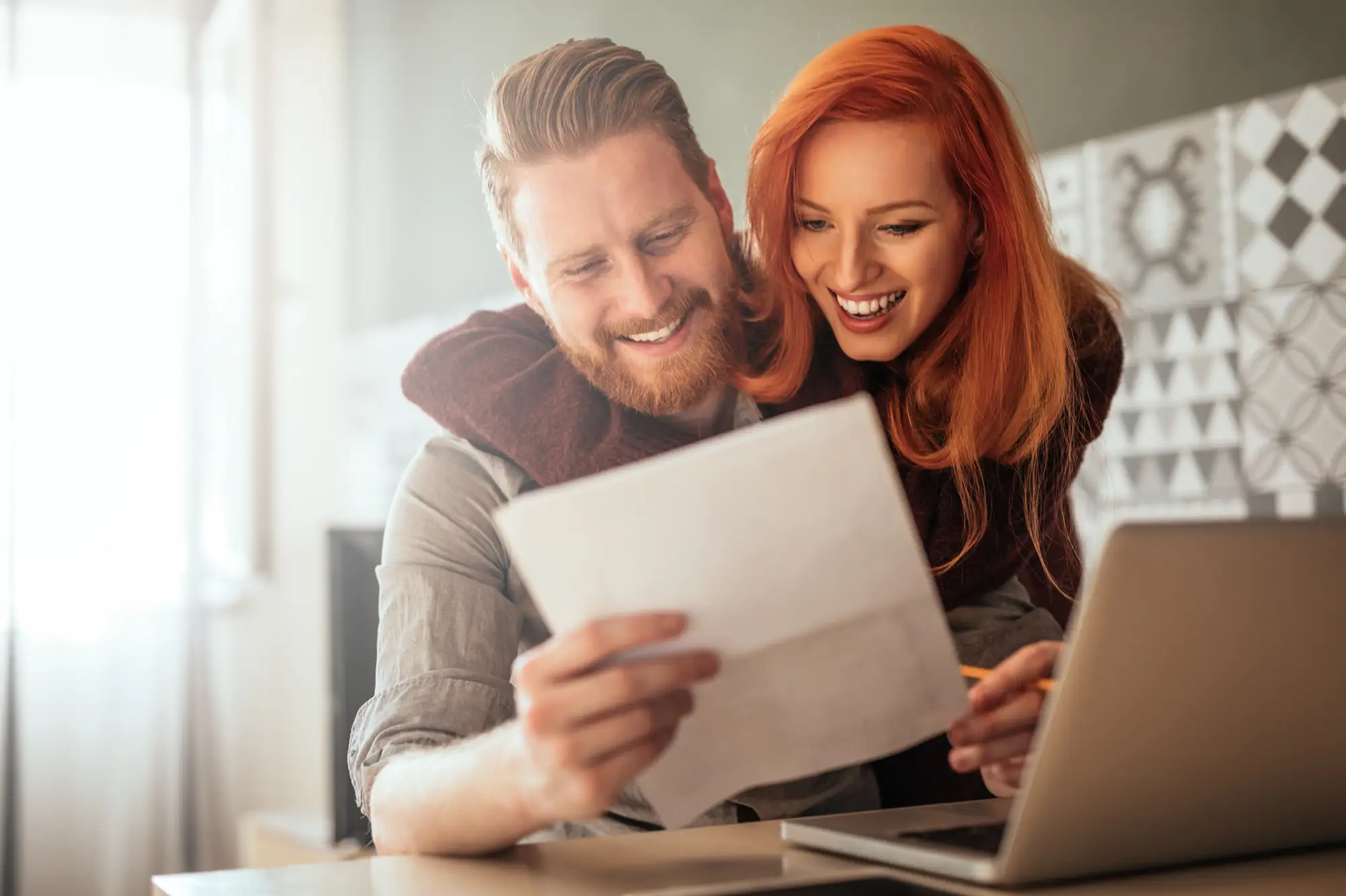 couple smiling while looking at a piece of paper