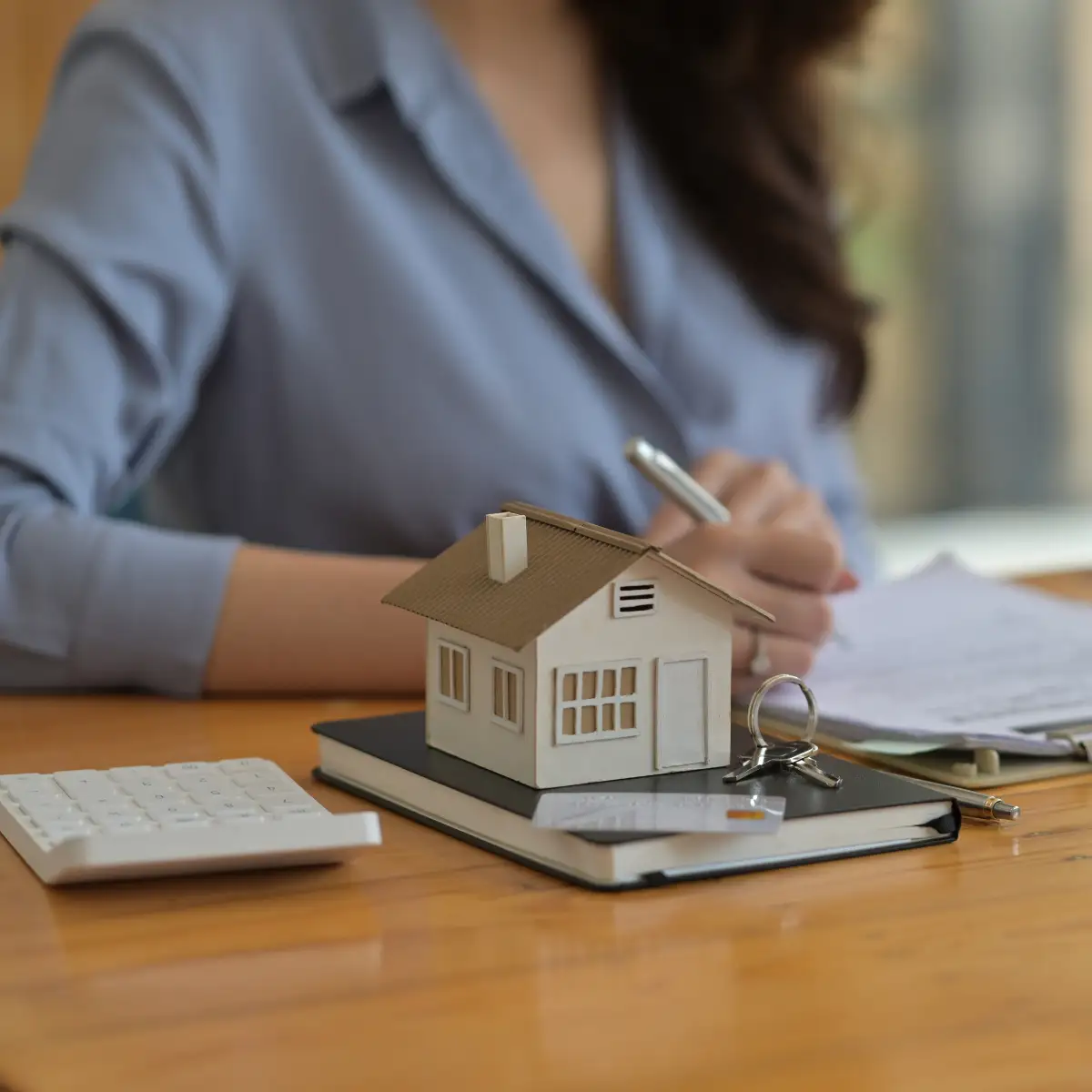 woman at desk with wooden home and keys