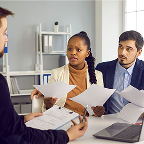 couple unhappy looking at documents with agent