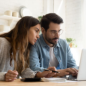 man and woman researching homes on laptop