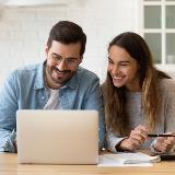 man and woman smiling at laptop after being accepted for an FHA loan
